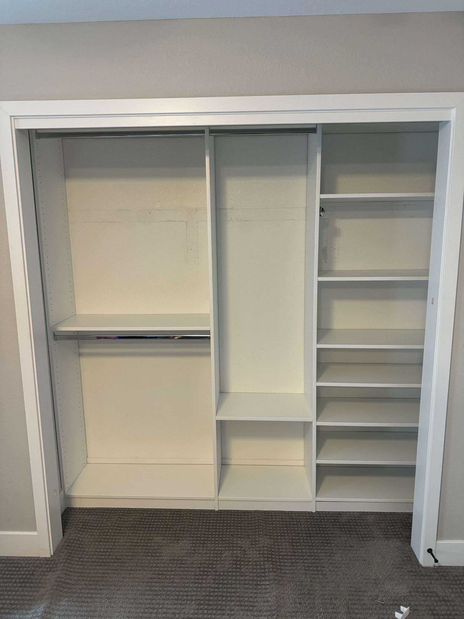 An empty closet with white shelves and a gray carpet.
