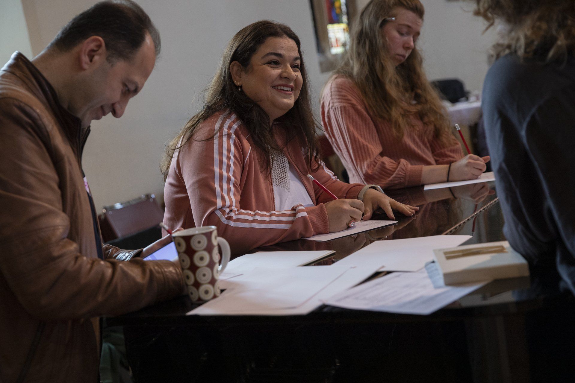 A group of people are sitting at a table writing on papers.