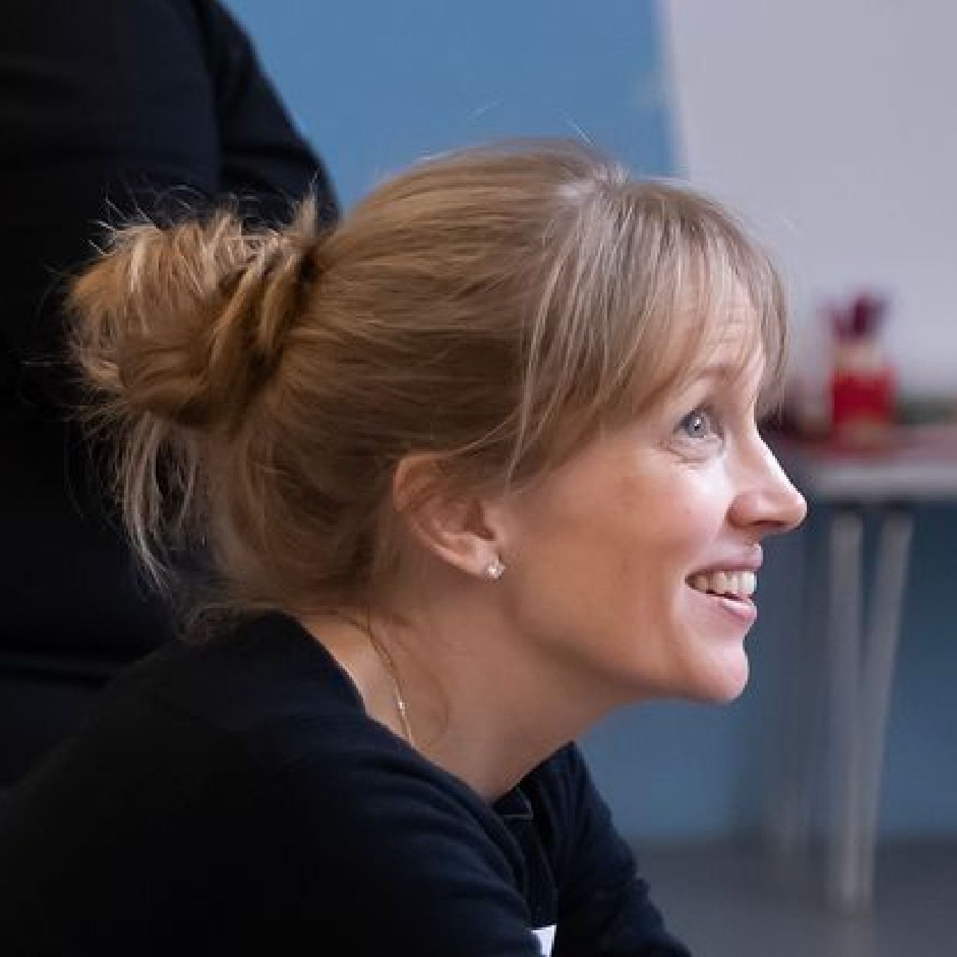 A woman with blonde hair in a bun is smiling
