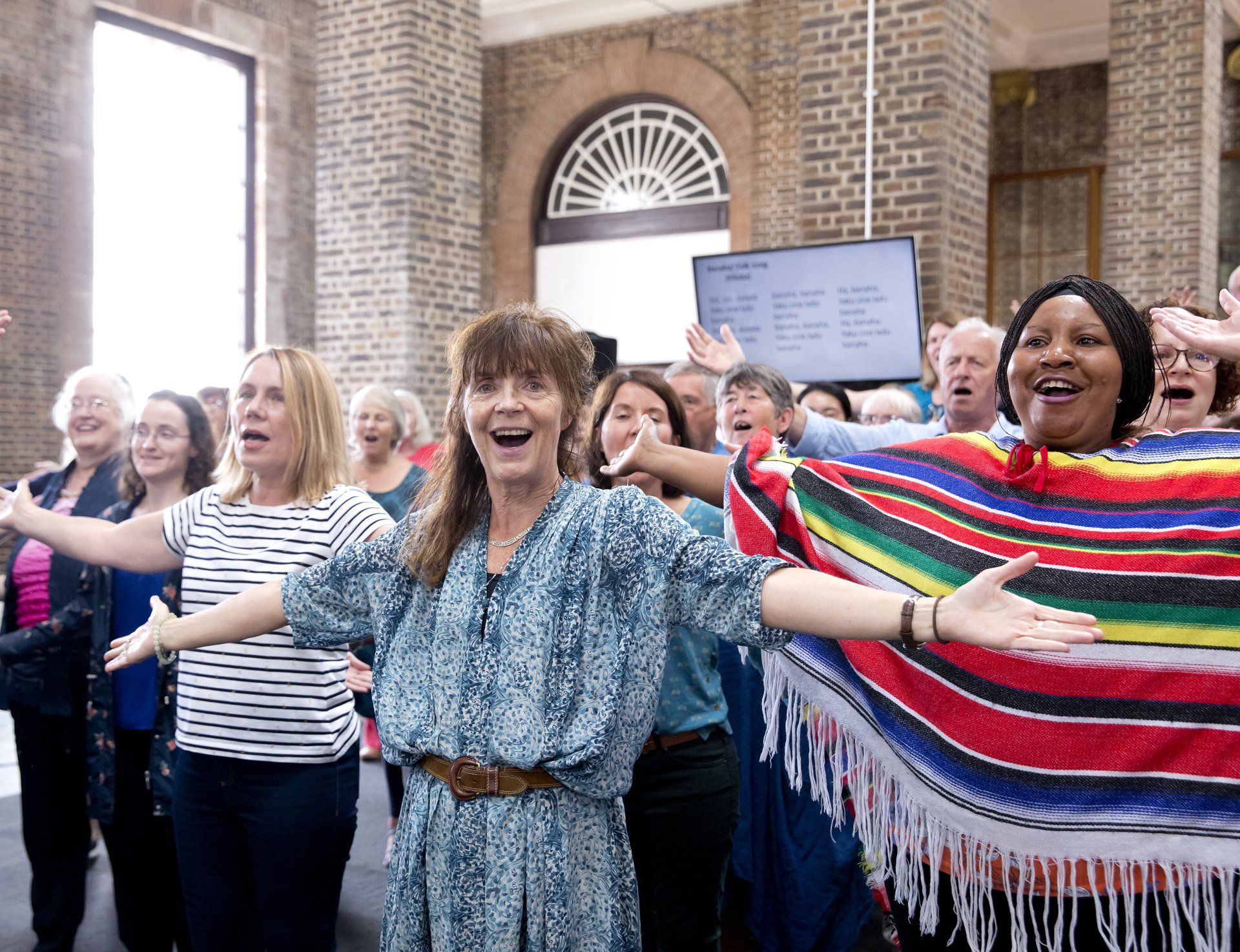 A group of people are standing in a room with their arms outstretched.