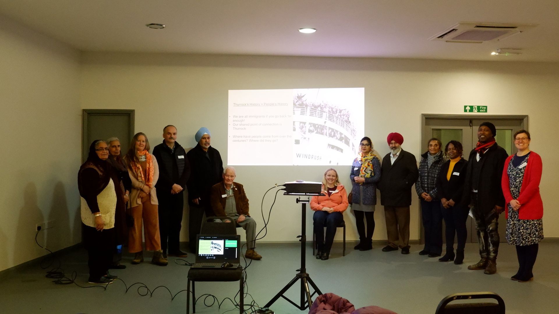 A group of people are standing in front of a projector screen.