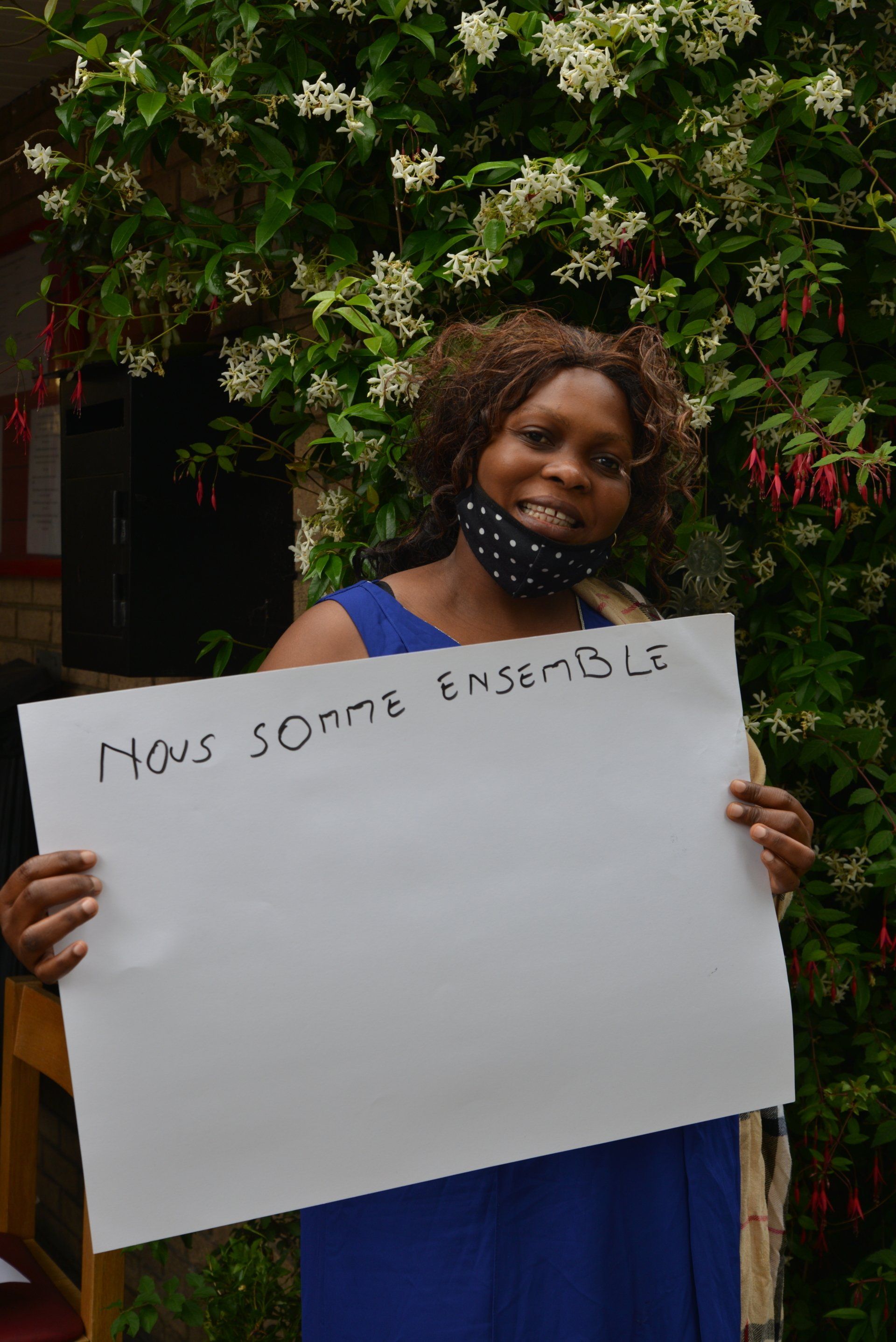 A woman in a blue dress is holding a sign that says nous somme ensemble.
