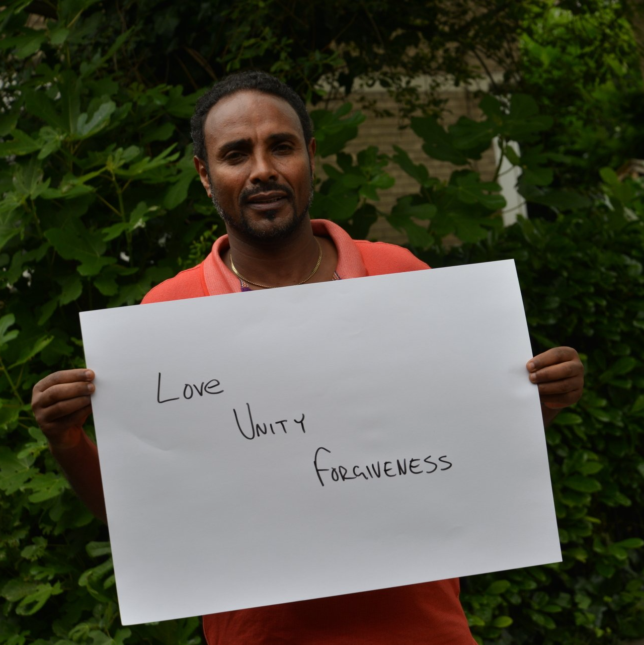 A man is holding a sign that says love unity forgiveness