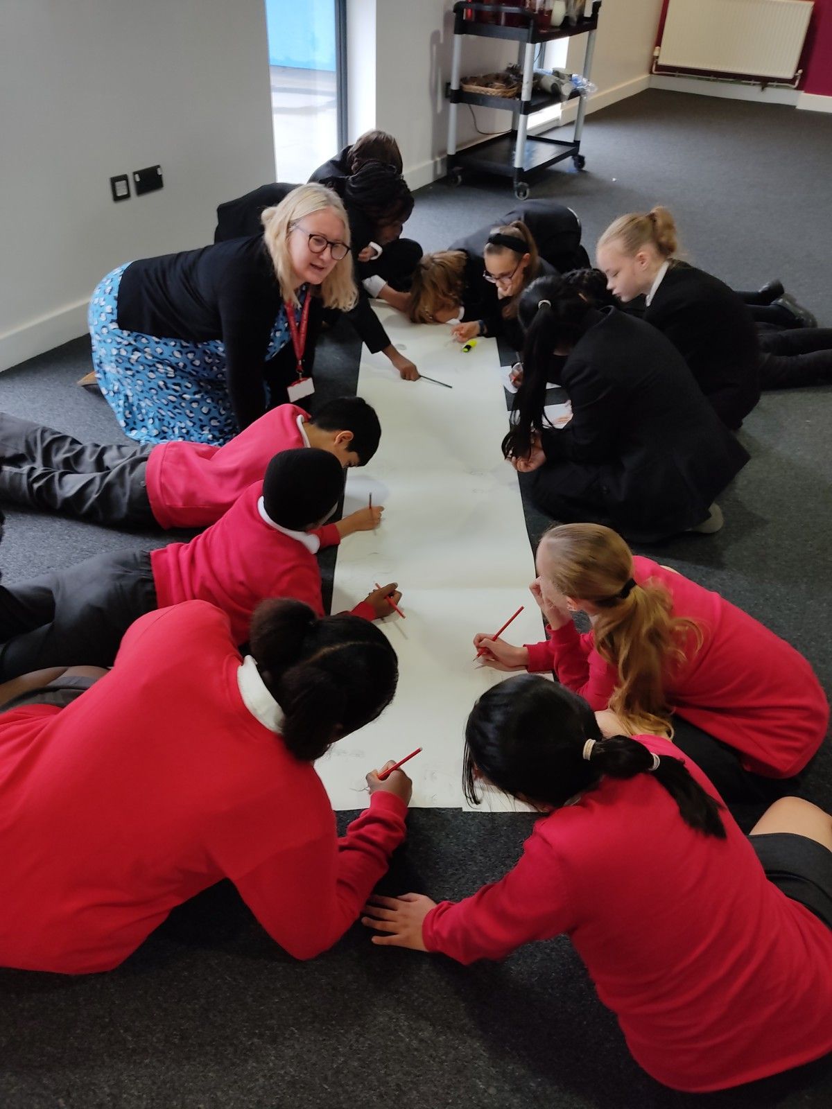 A group of children are laying on the floor writing on a piece of paper