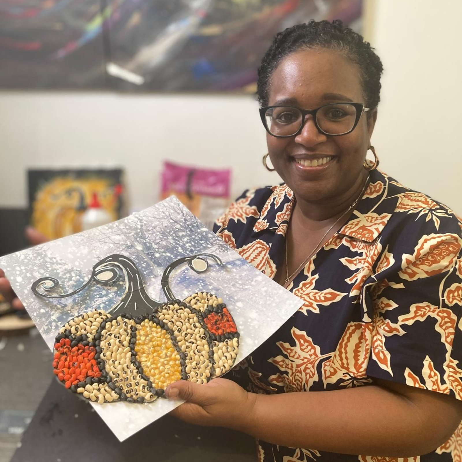 A woman wearing a black leather jacket and geometric patterned scarf is smiling for the camera
