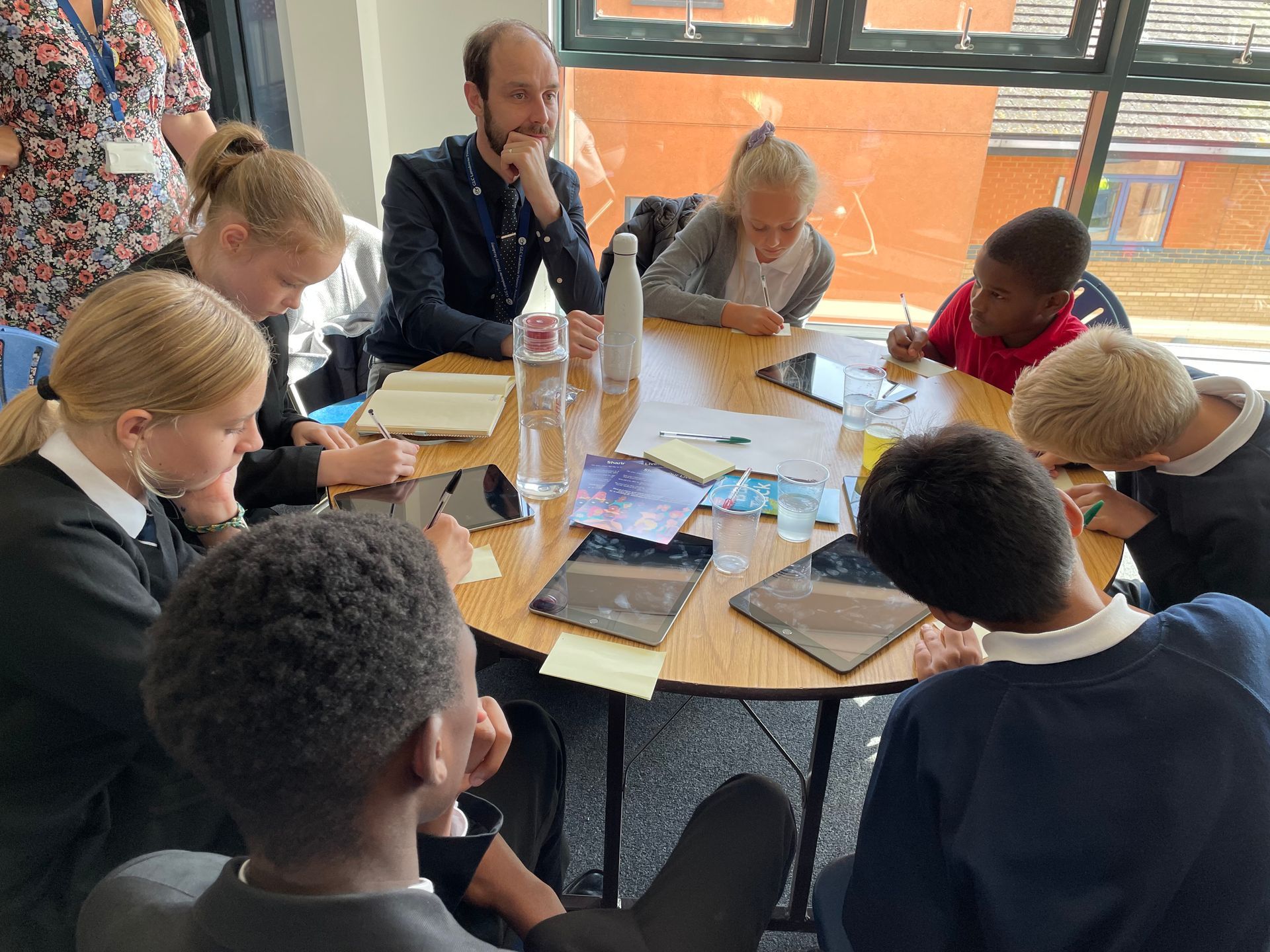 A group of people are sitting around a table using tablets.