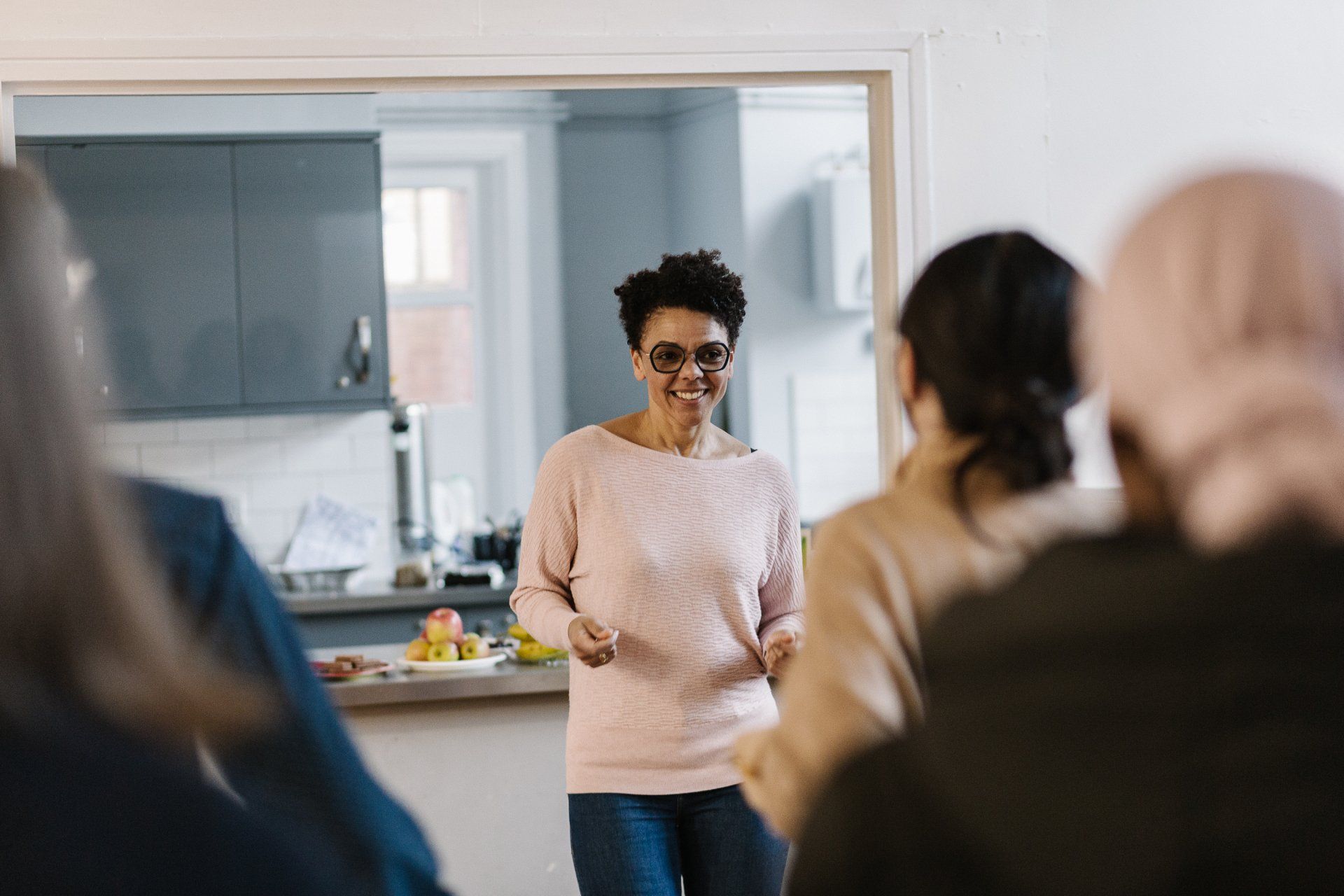 A woman in a pink sweater is standing in front of a group of people.