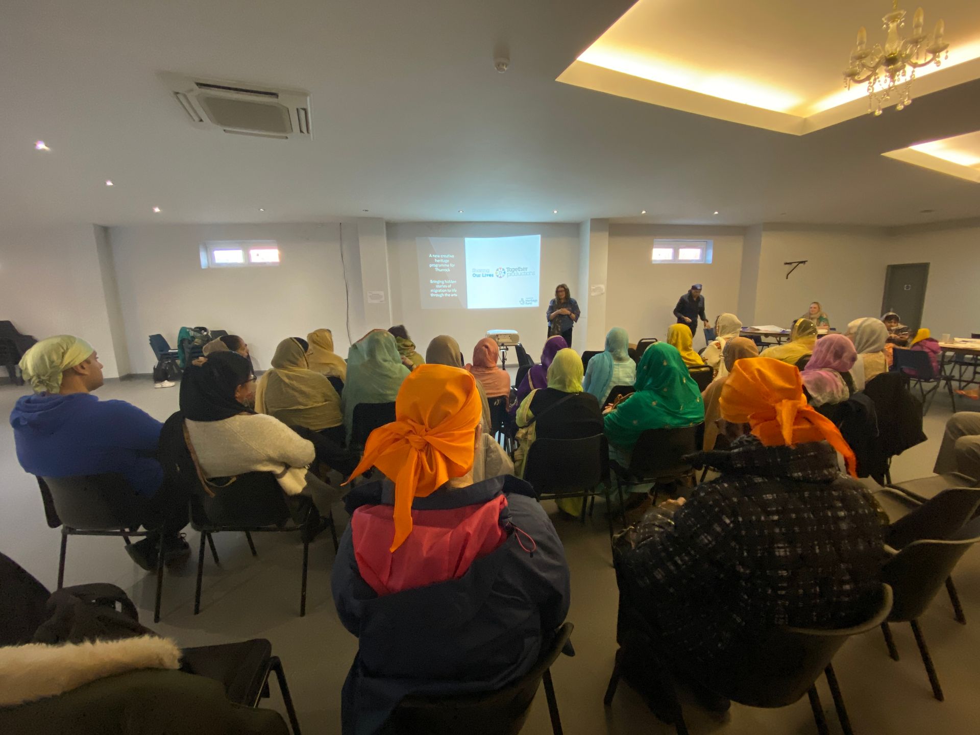 A group of people are sitting in chairs in a room watching a presentation.
