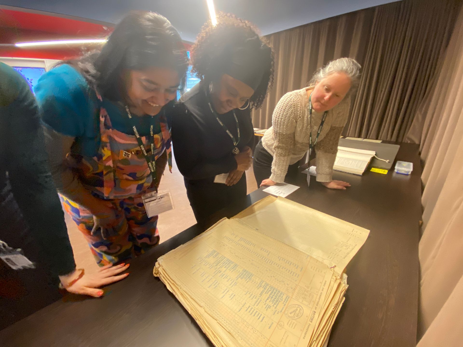 Three women are looking at a large piece of paper on a table.