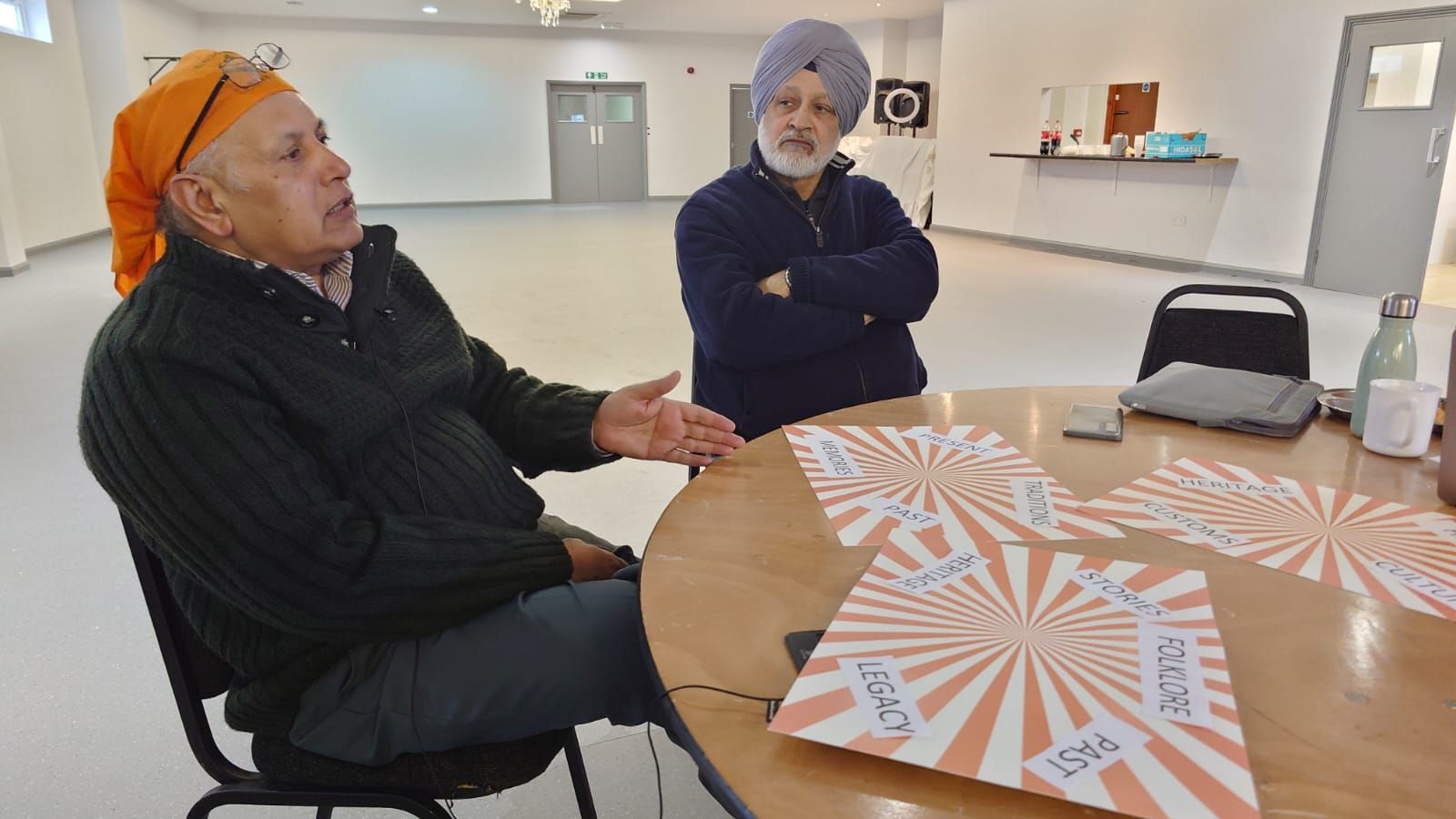 Two men are sitting at a table talking to each other