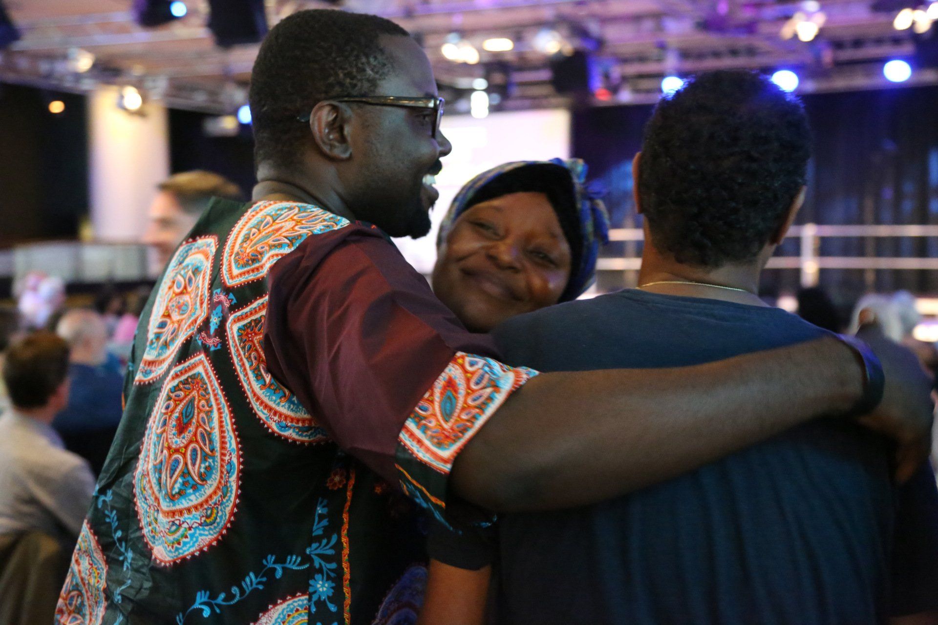 A group of people are hugging each other in a room.