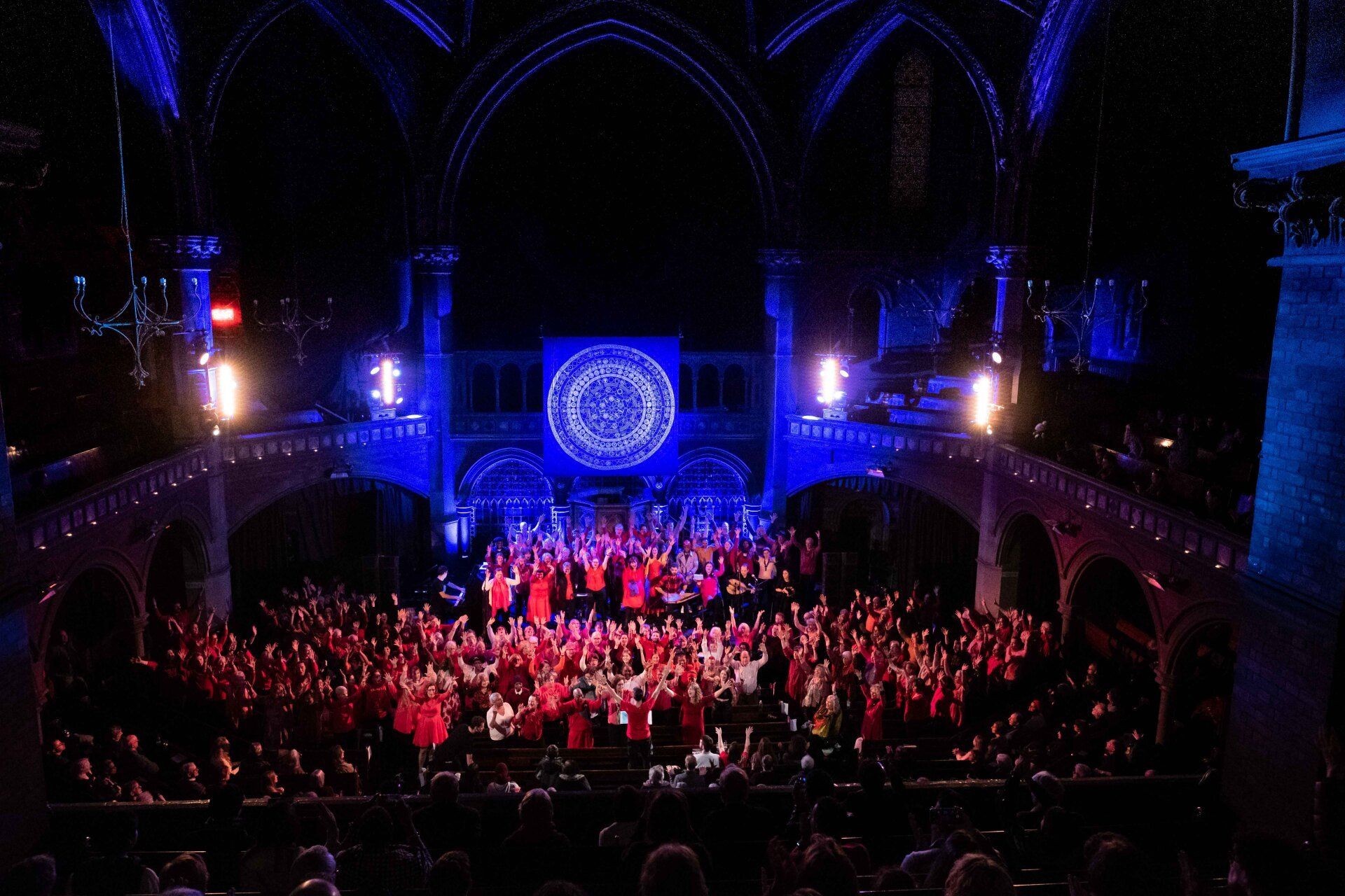 A large group of people are gathered in a dark auditorium.