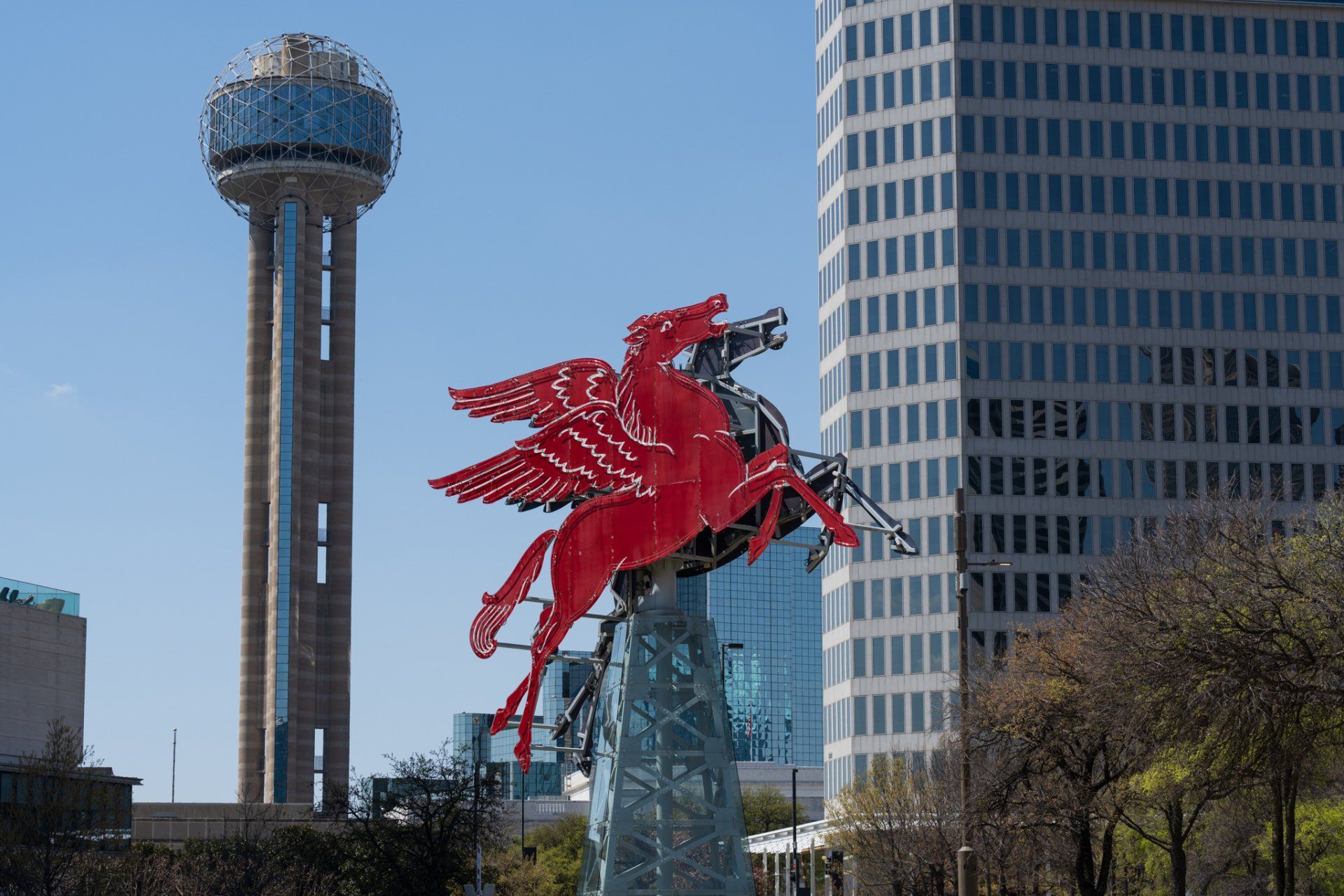a statue of a red pegasus is in front of a tall building .
