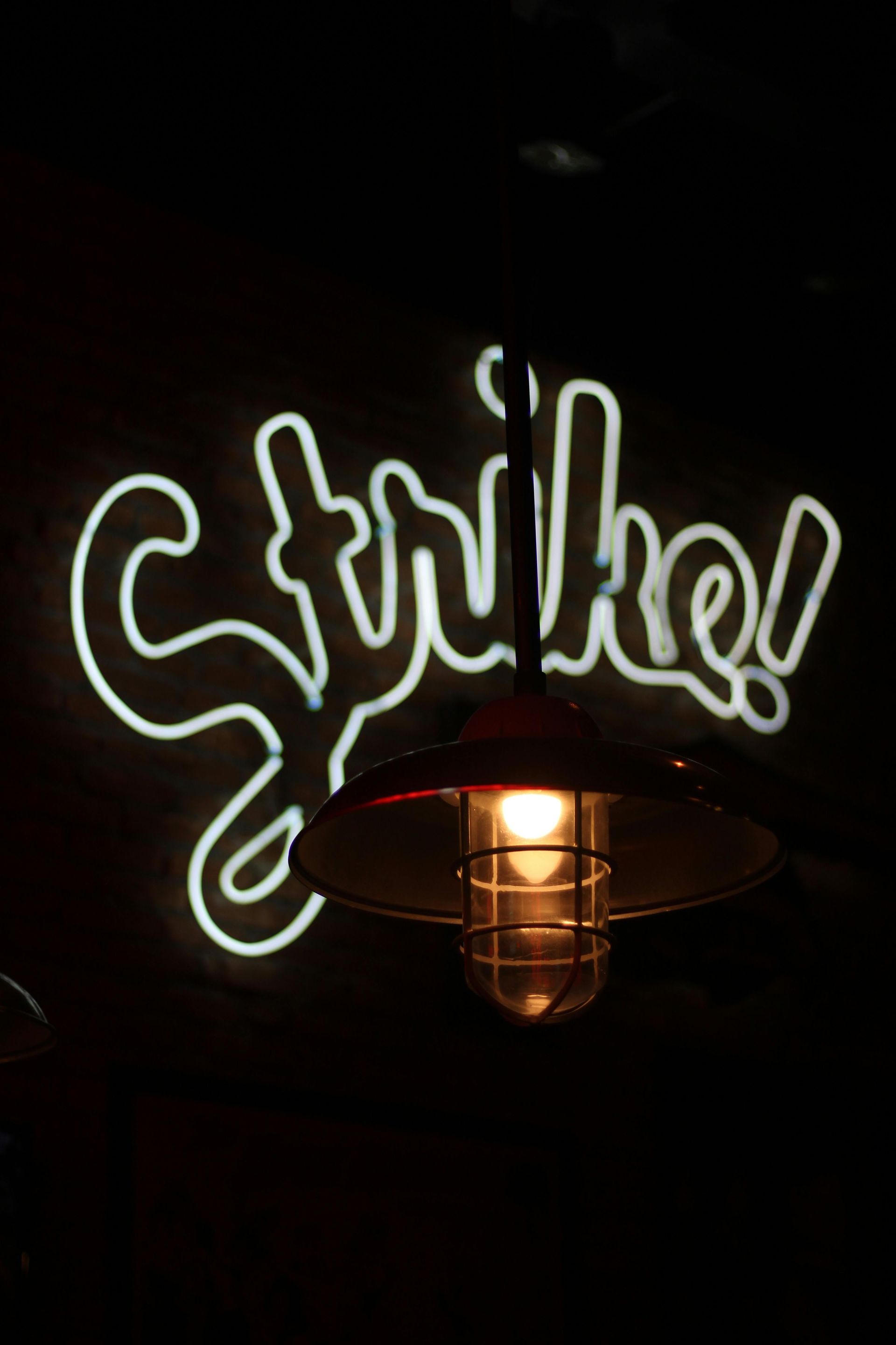 A hanging light with cage around bulb in front of a 