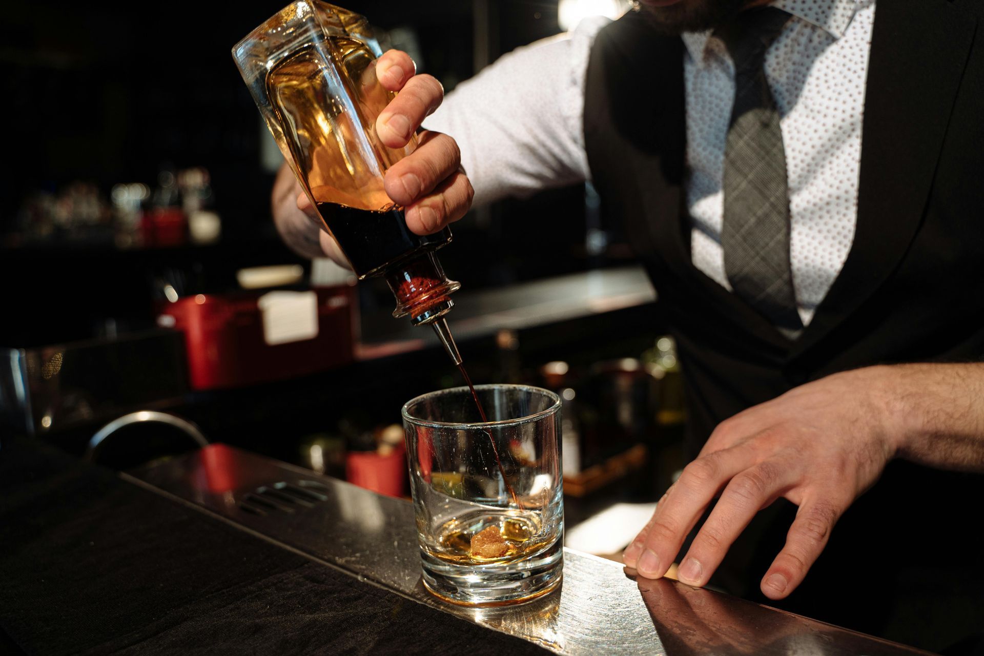 A bartender is pouring whiskey into a glass at a bar.