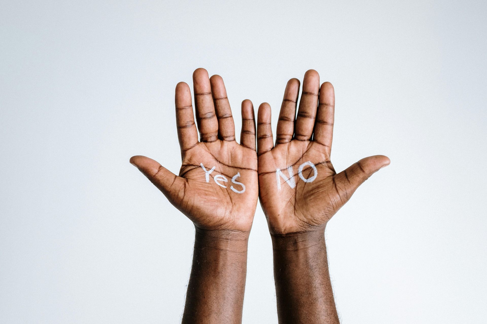 A person is holding up their hands with the words yes and no written on them.