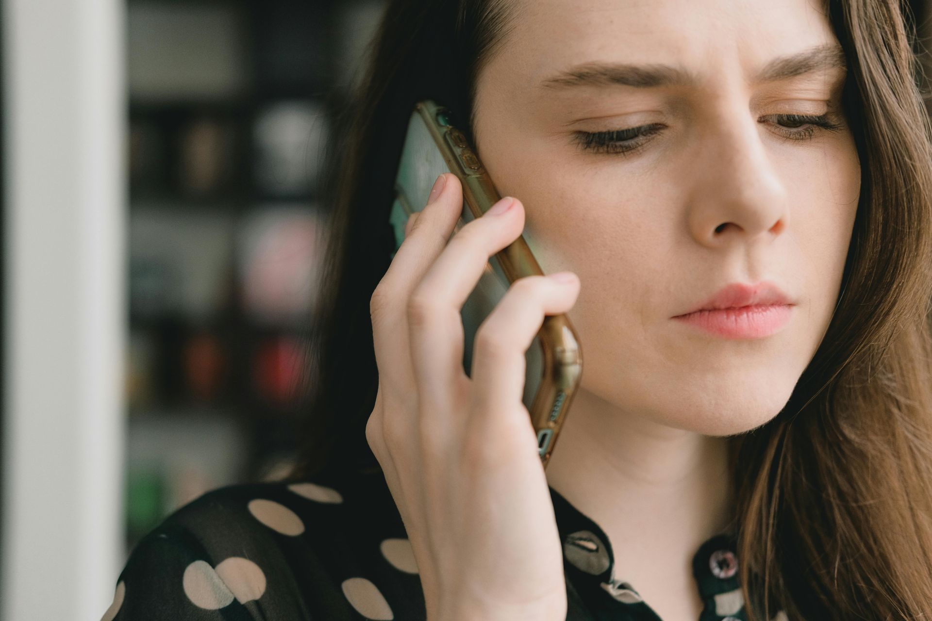 Woman on a phone call, looking concerned indoors