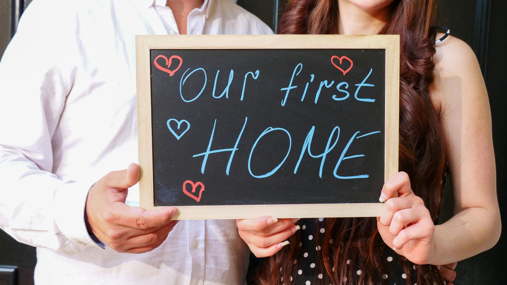 A man and a woman are holding a sign that says `` our first home ''.