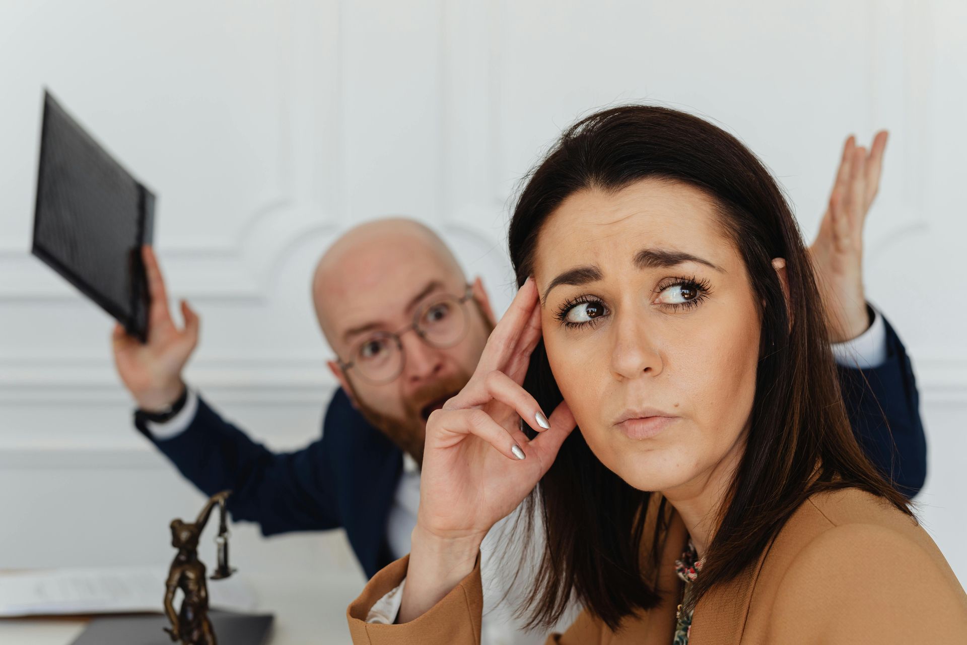 Husband and wife one holding a tablet and another looking worried in the foreground