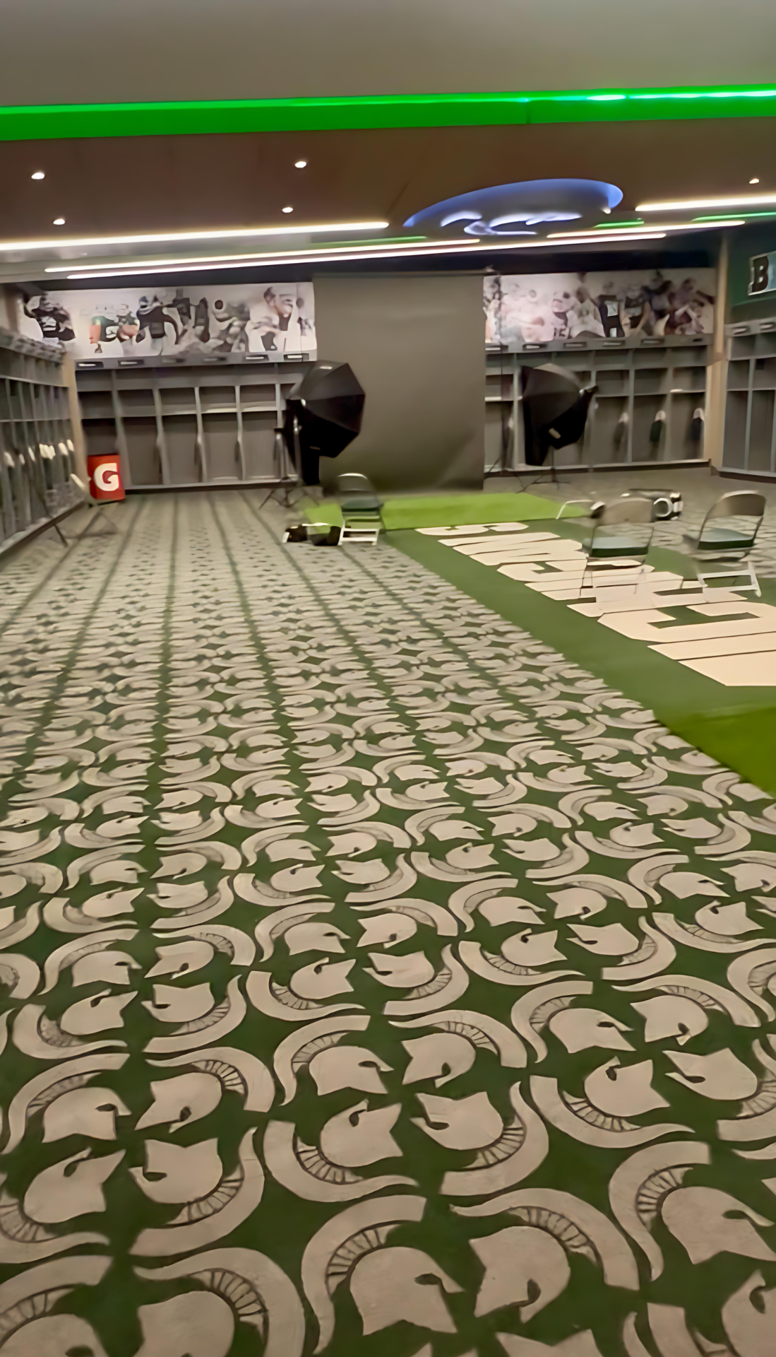 A locker room with a green carpet and a green light on the ceiling.