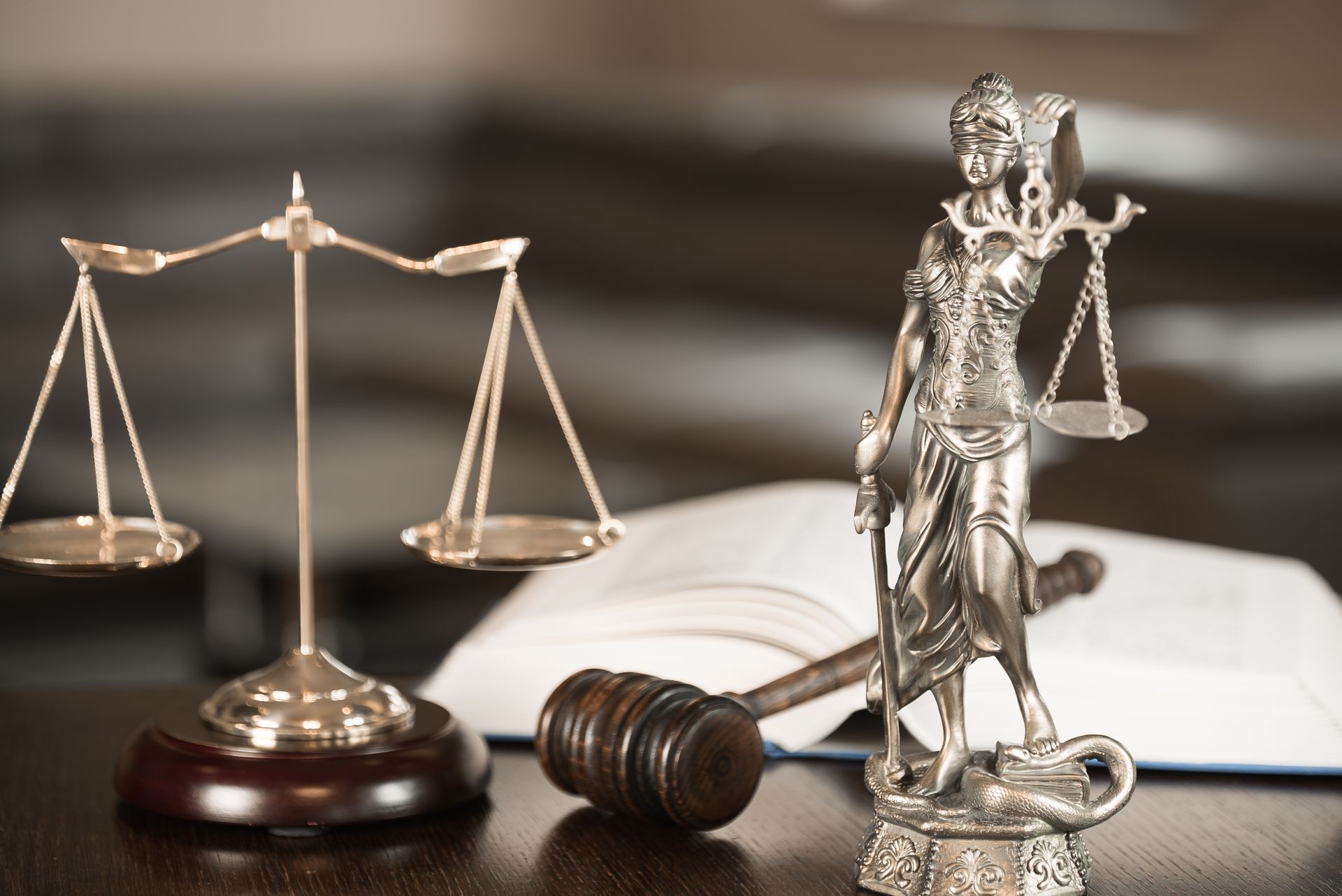 A statue of justice , scales of justice and a gavel on a table.