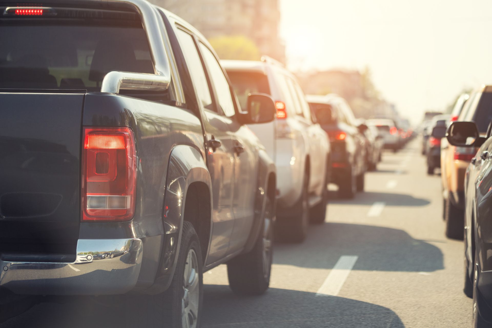 A row of cars are driving down a highway in traffic.