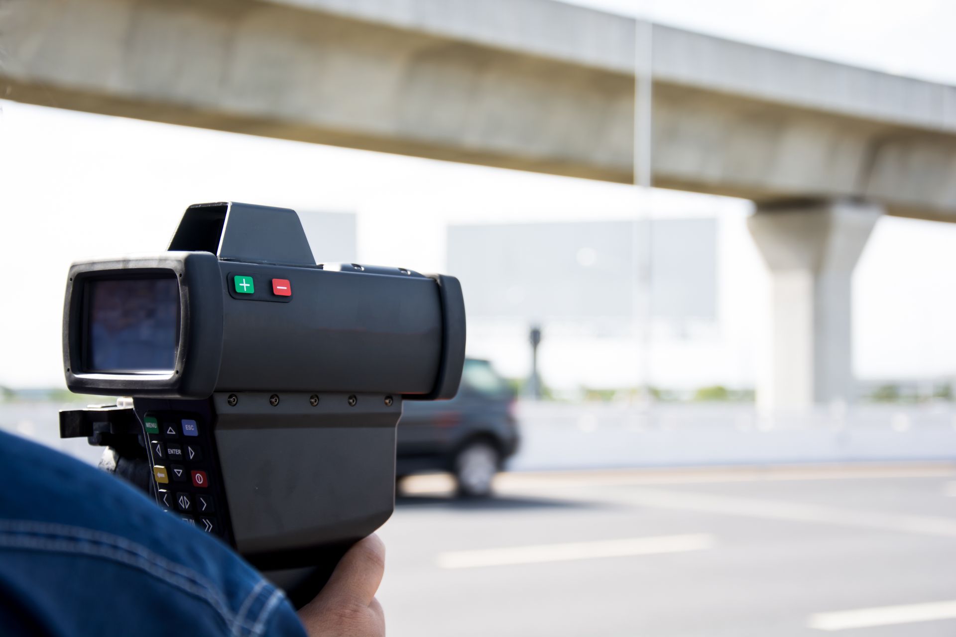 A person is holding a speed camera on a highway.