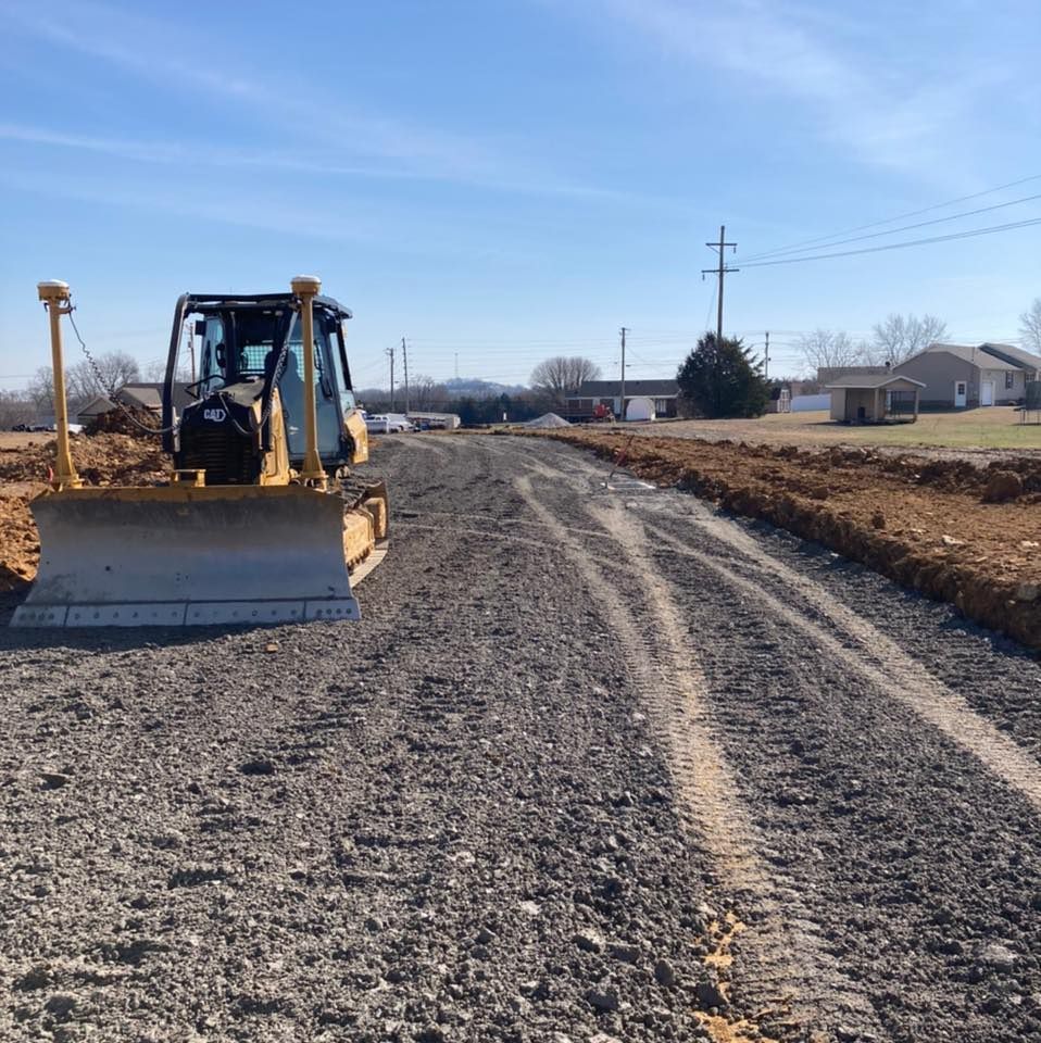 A yellow bulldozer parked on a gravel construction site under a clear blue sky.