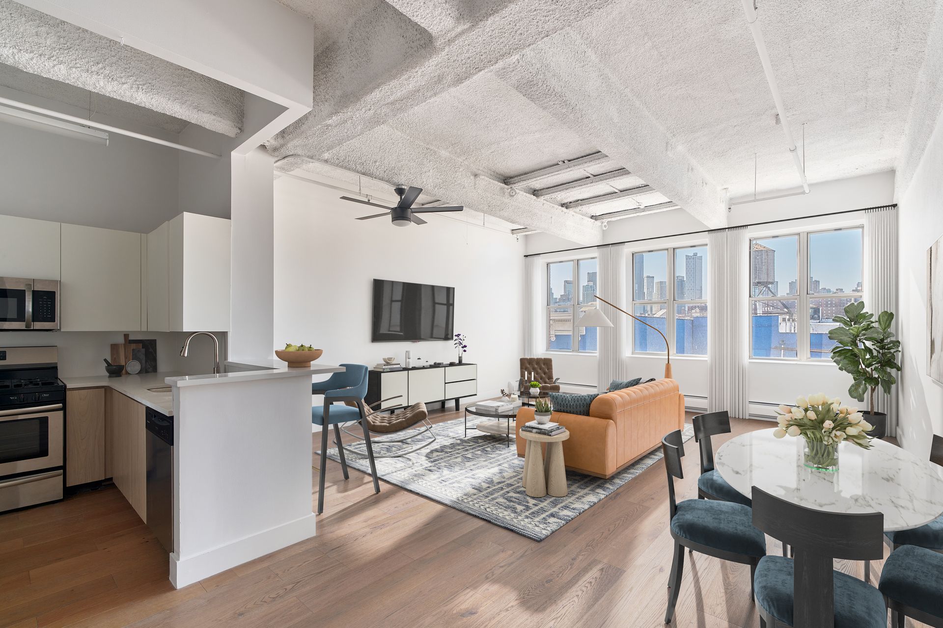 Modern loft apartment interior with kitchen, living area, and dining space; large windows with city view.