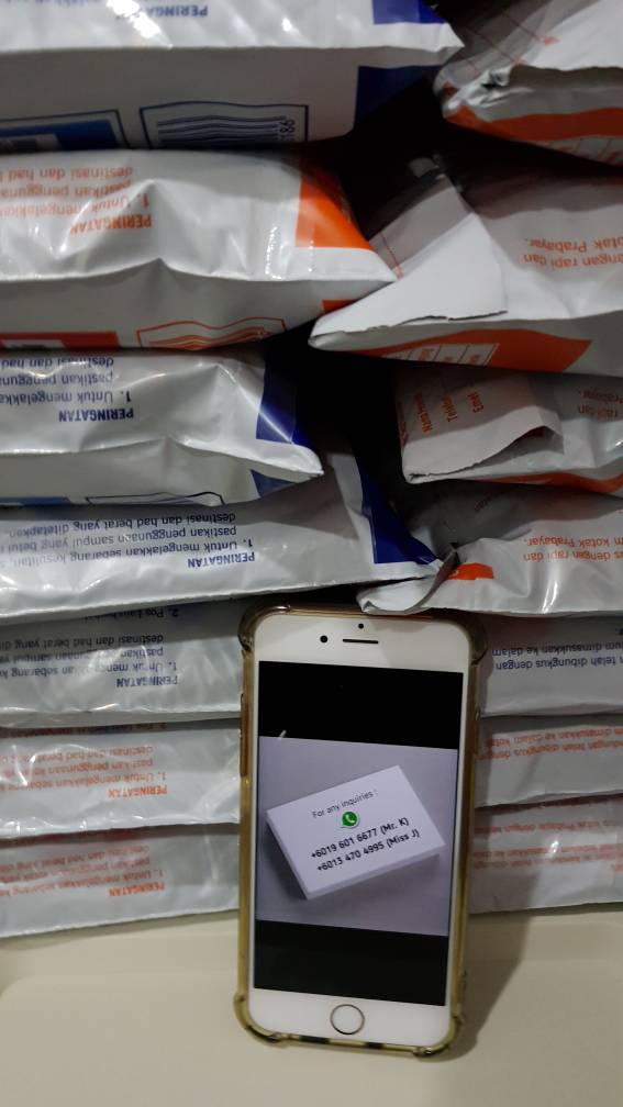 a stack of poslaju parcel with phone in the middle of it