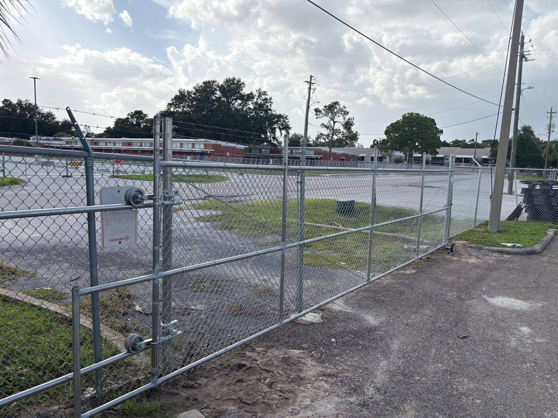 A white-painted concrete post and black wood fencing in the front yard of a resident's house