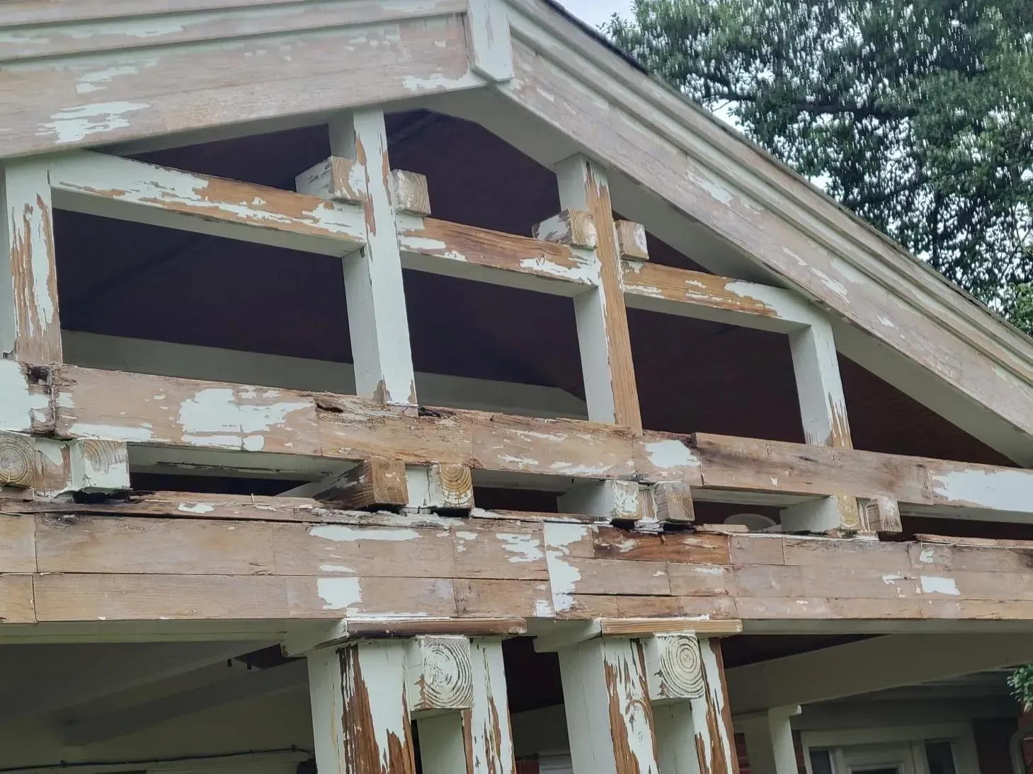 Weathered white and tan porch roof trim with peeling paint.