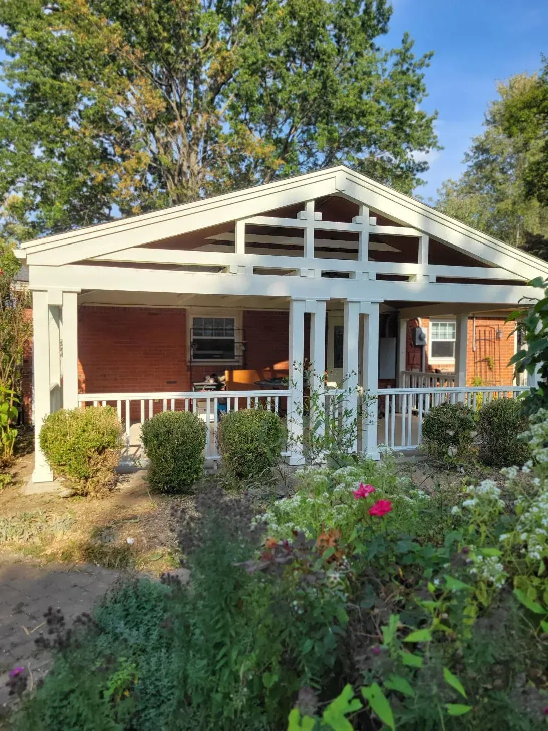 Brick house with white porch, garden in front.