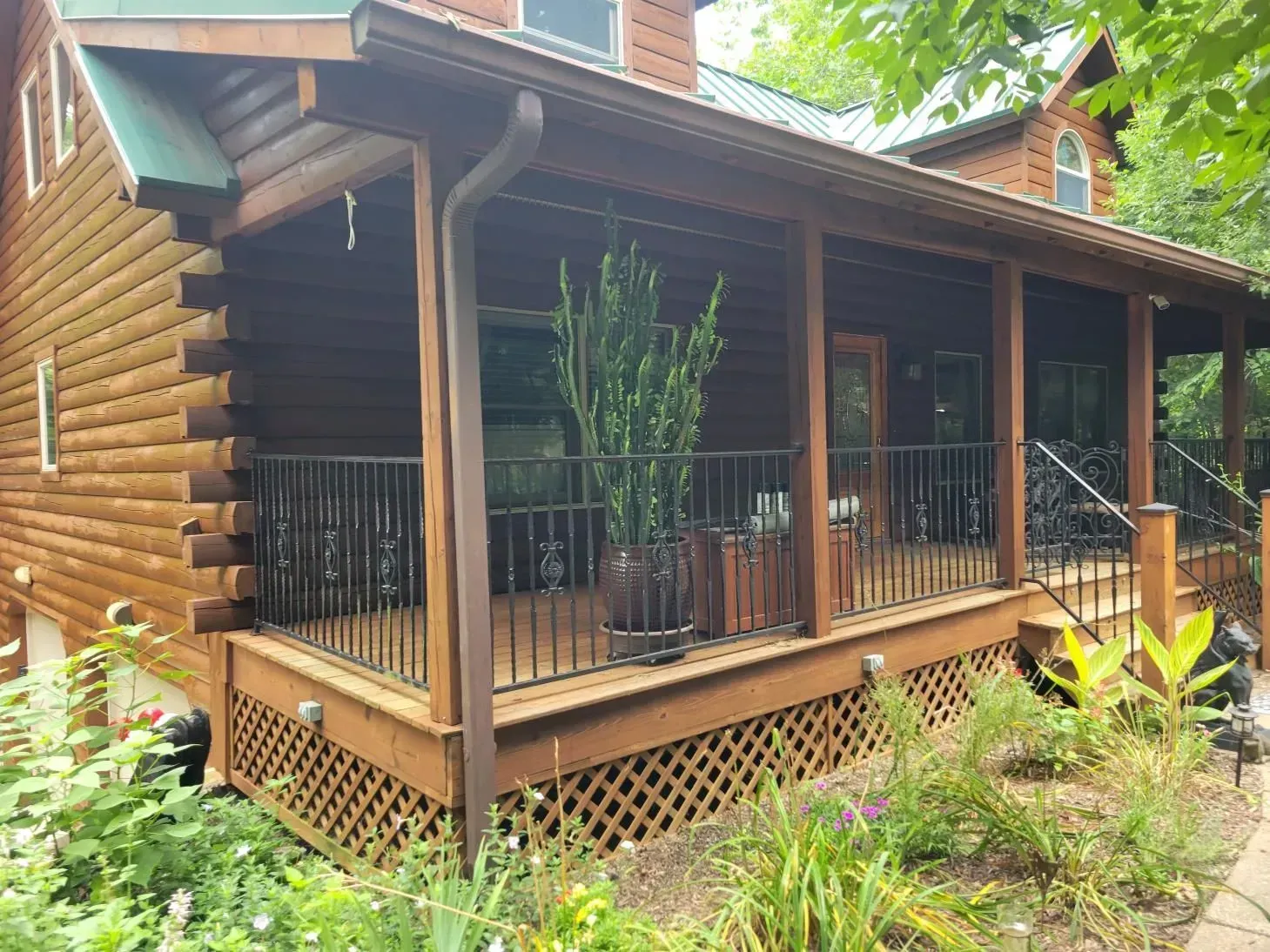 Wooden cabin with porch, dark railing, and large potted plant.