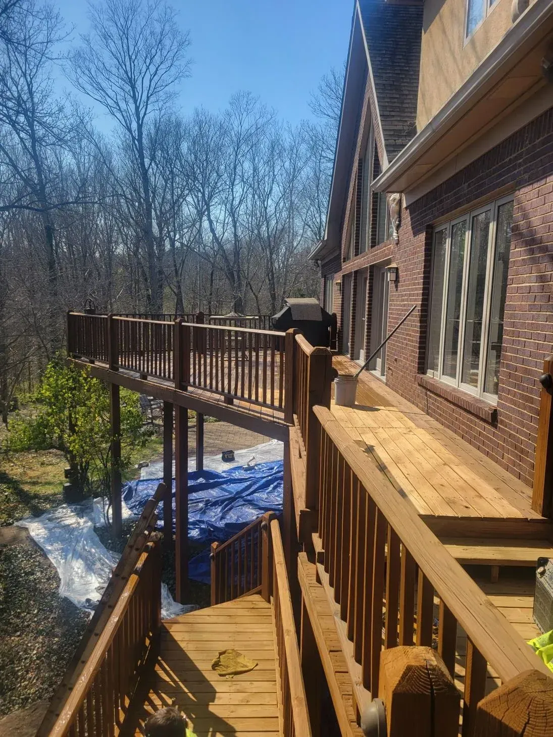 Wooden decks attached to a brick house overlooking a wooded area.