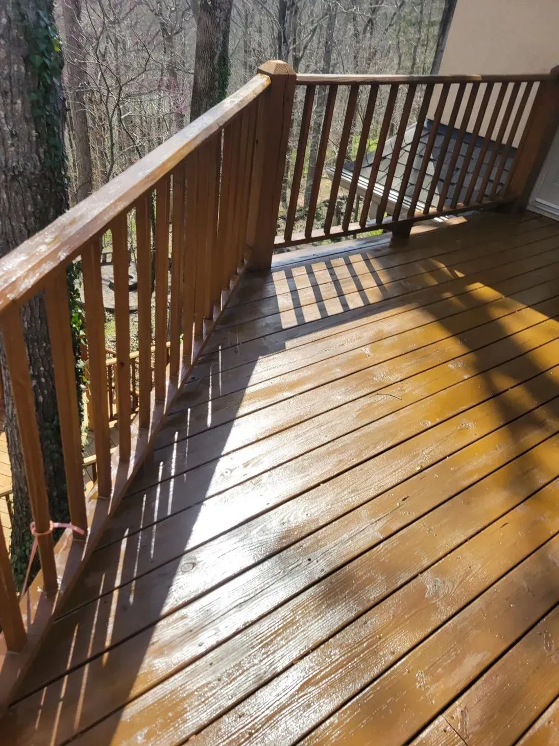 Wooden deck with brown railings, bathed in sunlight.