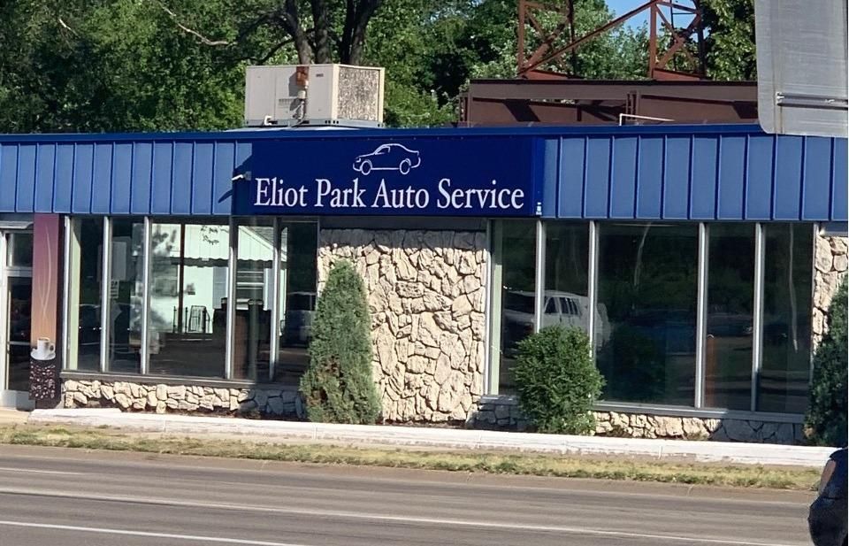 Eliot Park Auto Service building with blue awning, large windows, and stone facade.