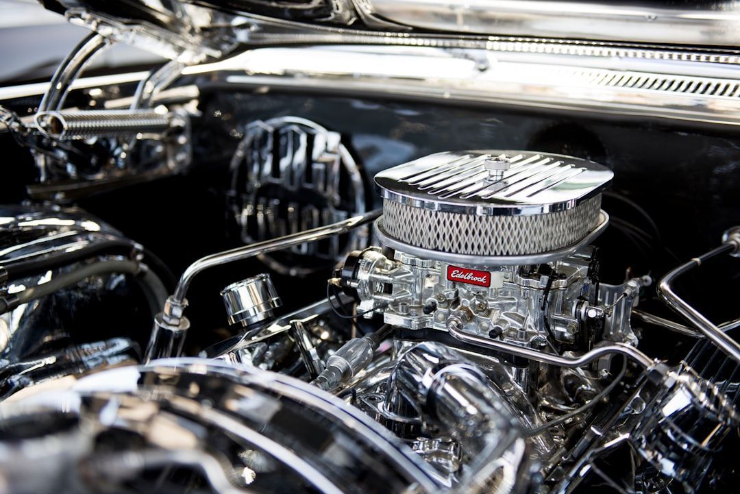 Close-up of a highly polished, chrome-plated car engine with a visible carburetor air cleaner and intricate metal parts.