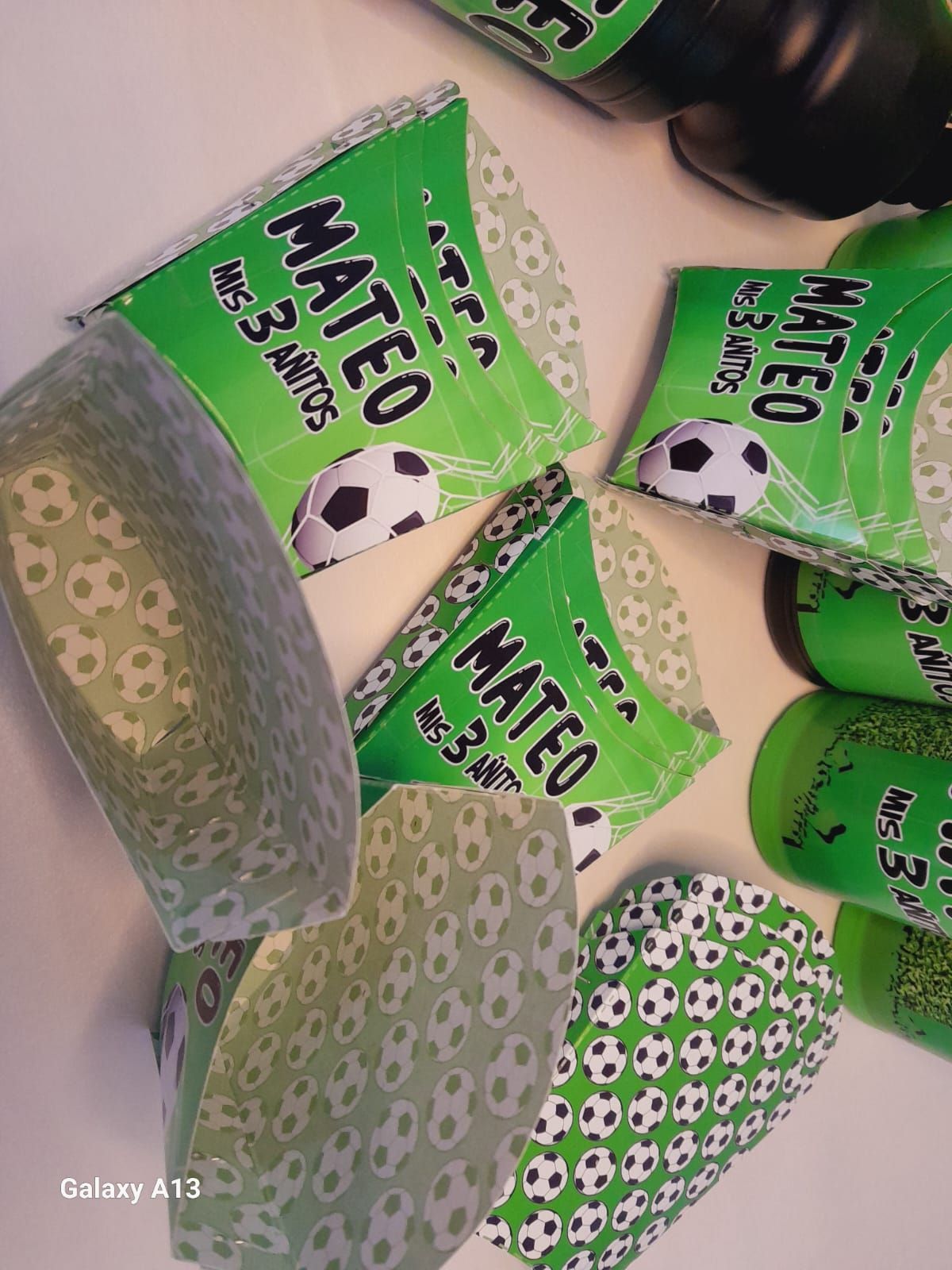 Recuerdos de fiesta con temática de fútbol verde y blanco para "Mateo" que cumple 3 años. Incluye cajas y botellas de refresco envueltas.
