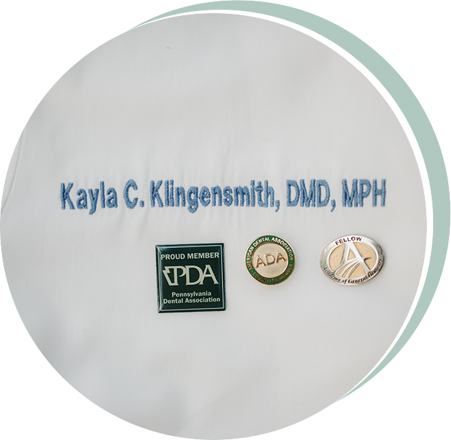 White lab coat embroidered with name, credentials, and professional pins.