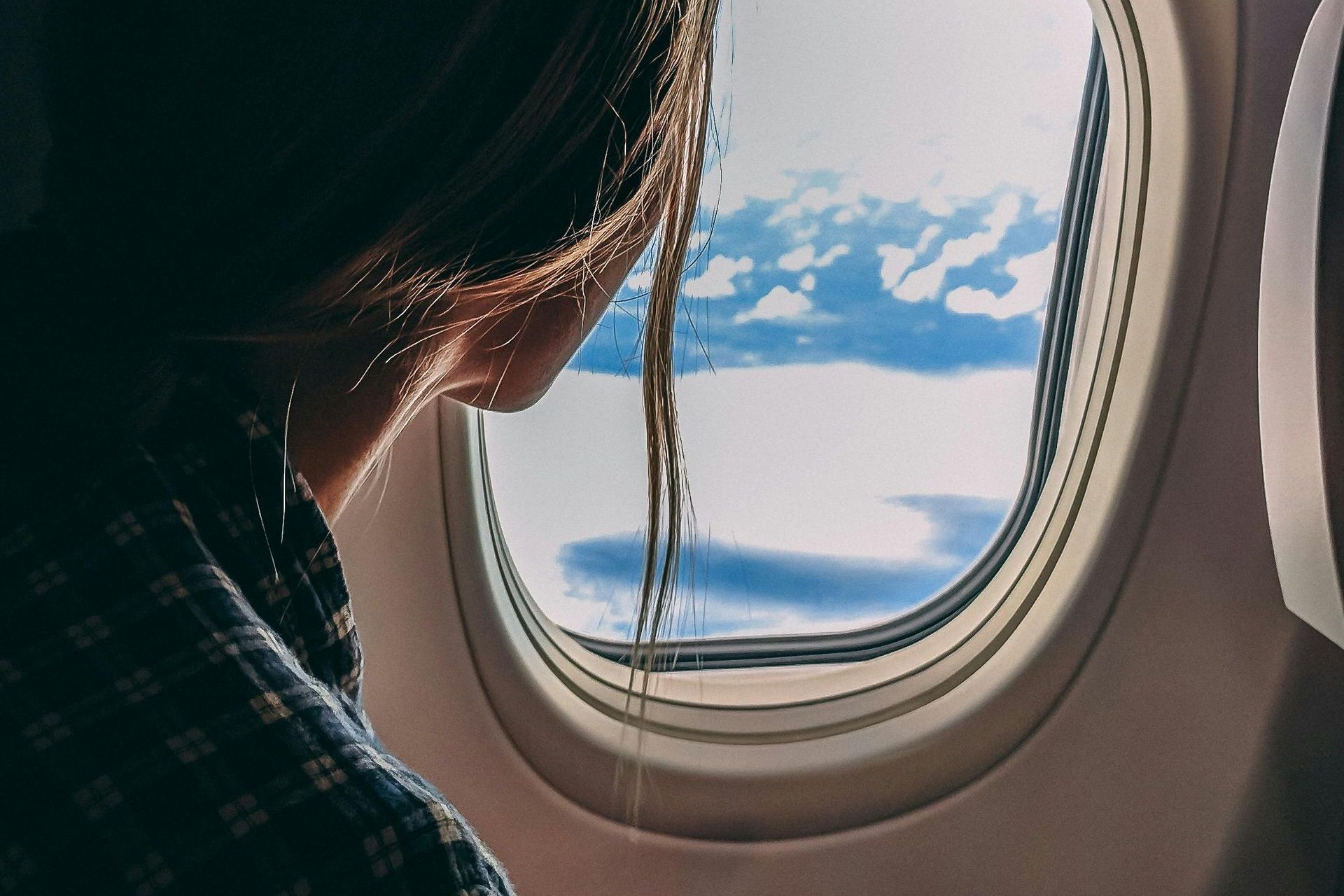 a gril on a plane looking out of the window after booking cheap vacations for couples