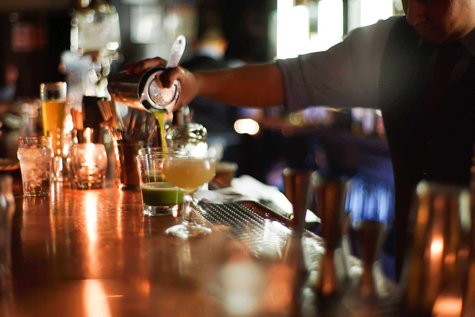 A bartender is pouring a drink into a glass at a bar.
