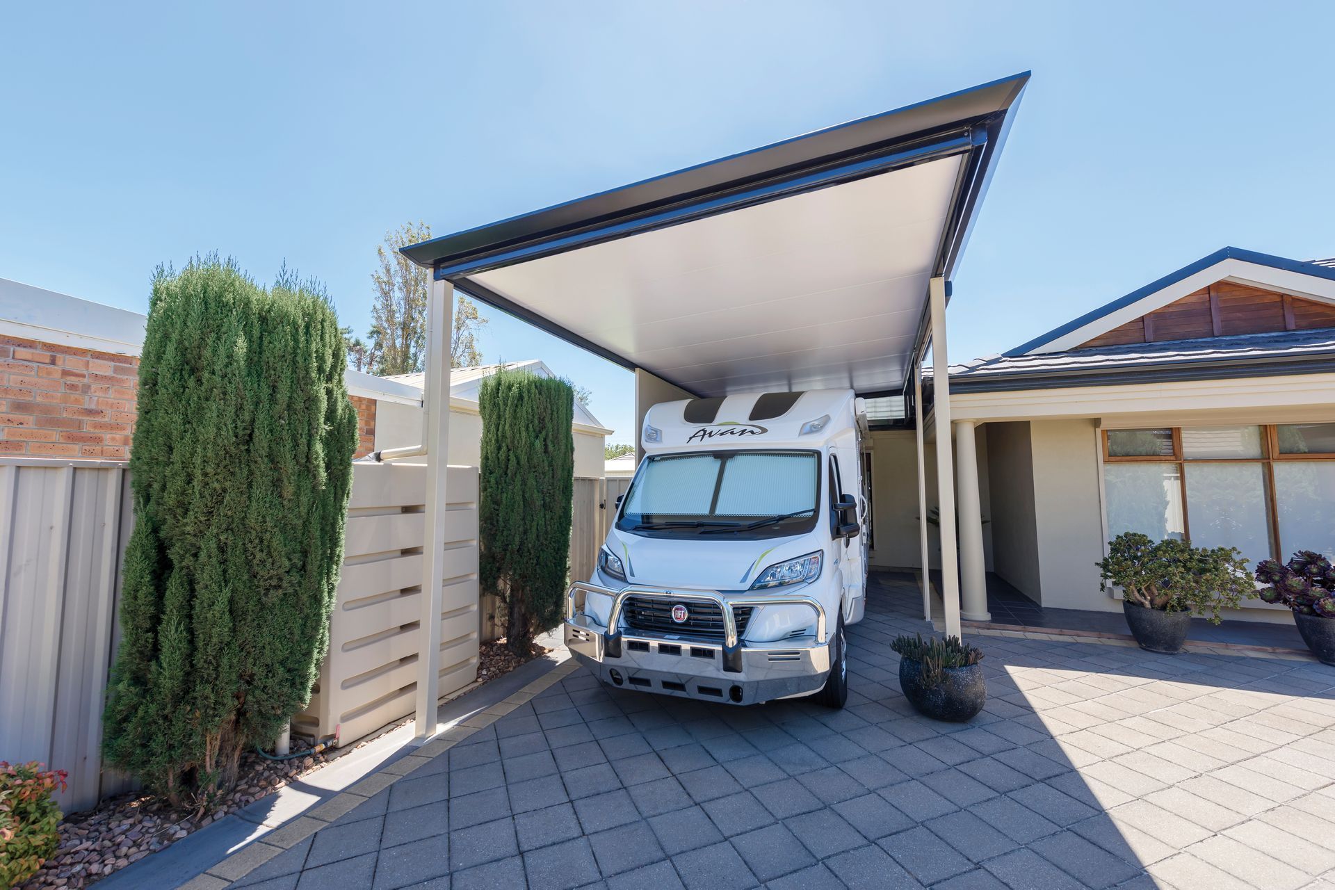 White camper van parked under a carport in a driveway, blue sky — Precision Patios Toowoomba In Toowoomba, QLD