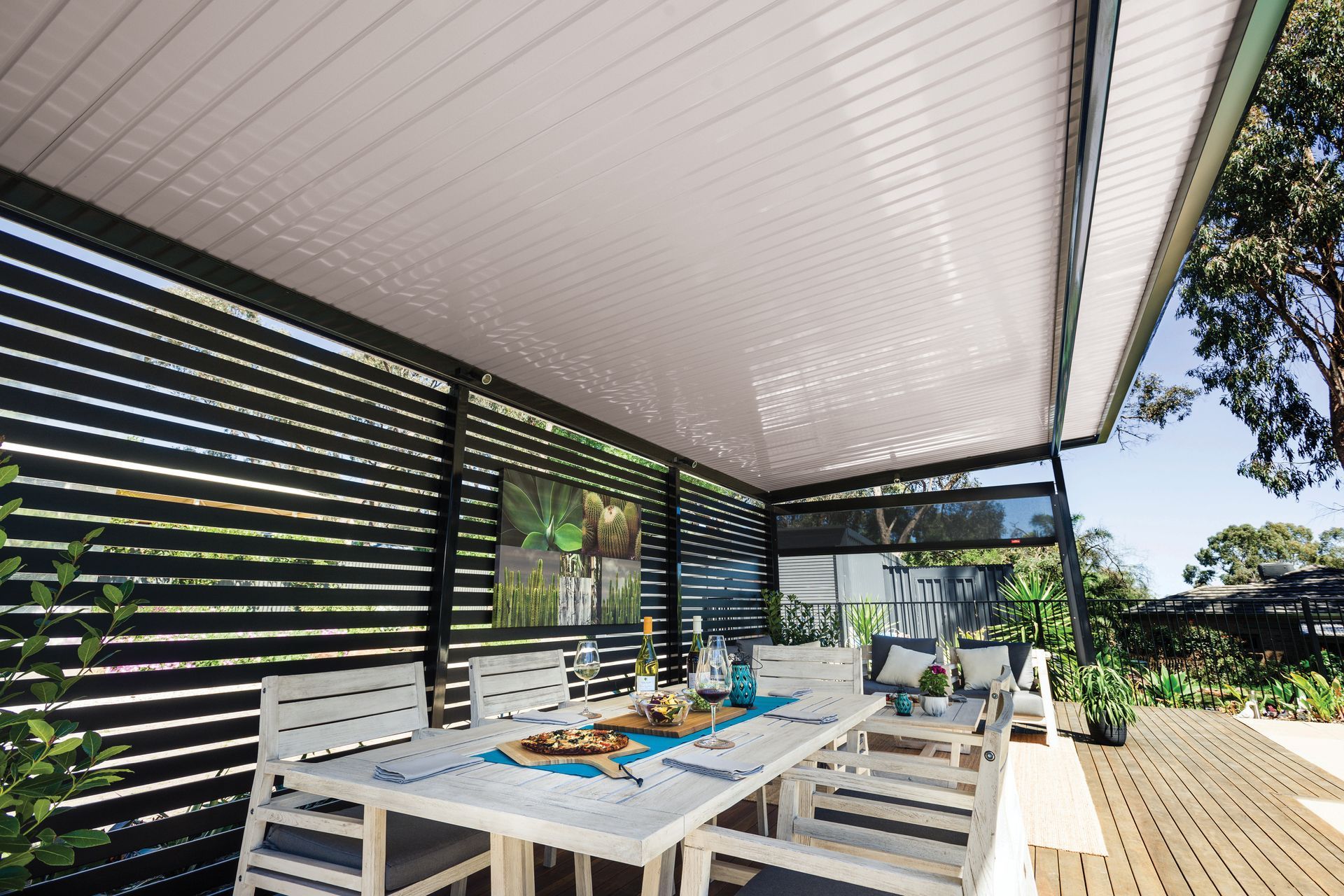 Outdoor dining area with white table, chairs, and slatted black privacy screen under a white roof — Precision Patios Toowoomba In Toowoomba, QLD