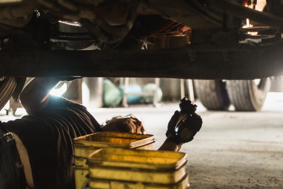 A man is working underneath a truck in a garage.