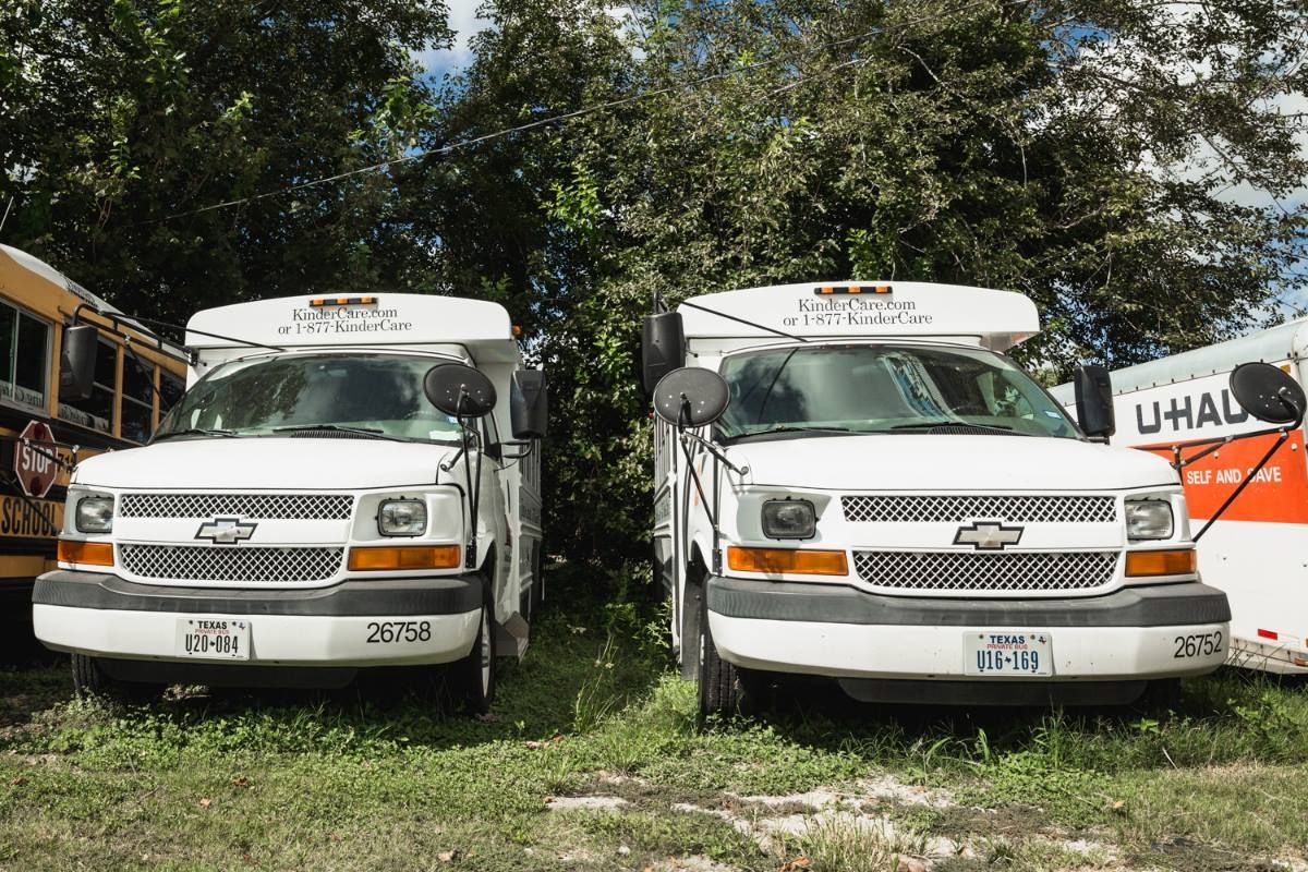 Two white vans are parked next to each other in a grassy field.