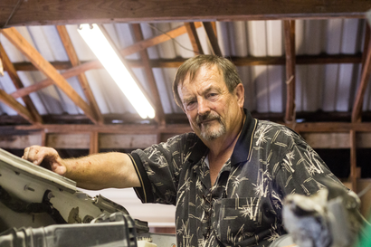 A man with a beard is working on a car in a garage.