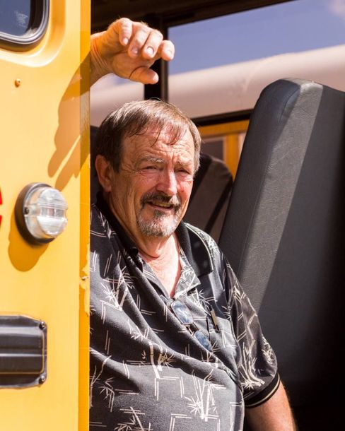 A man is leaning out of a yellow school bus