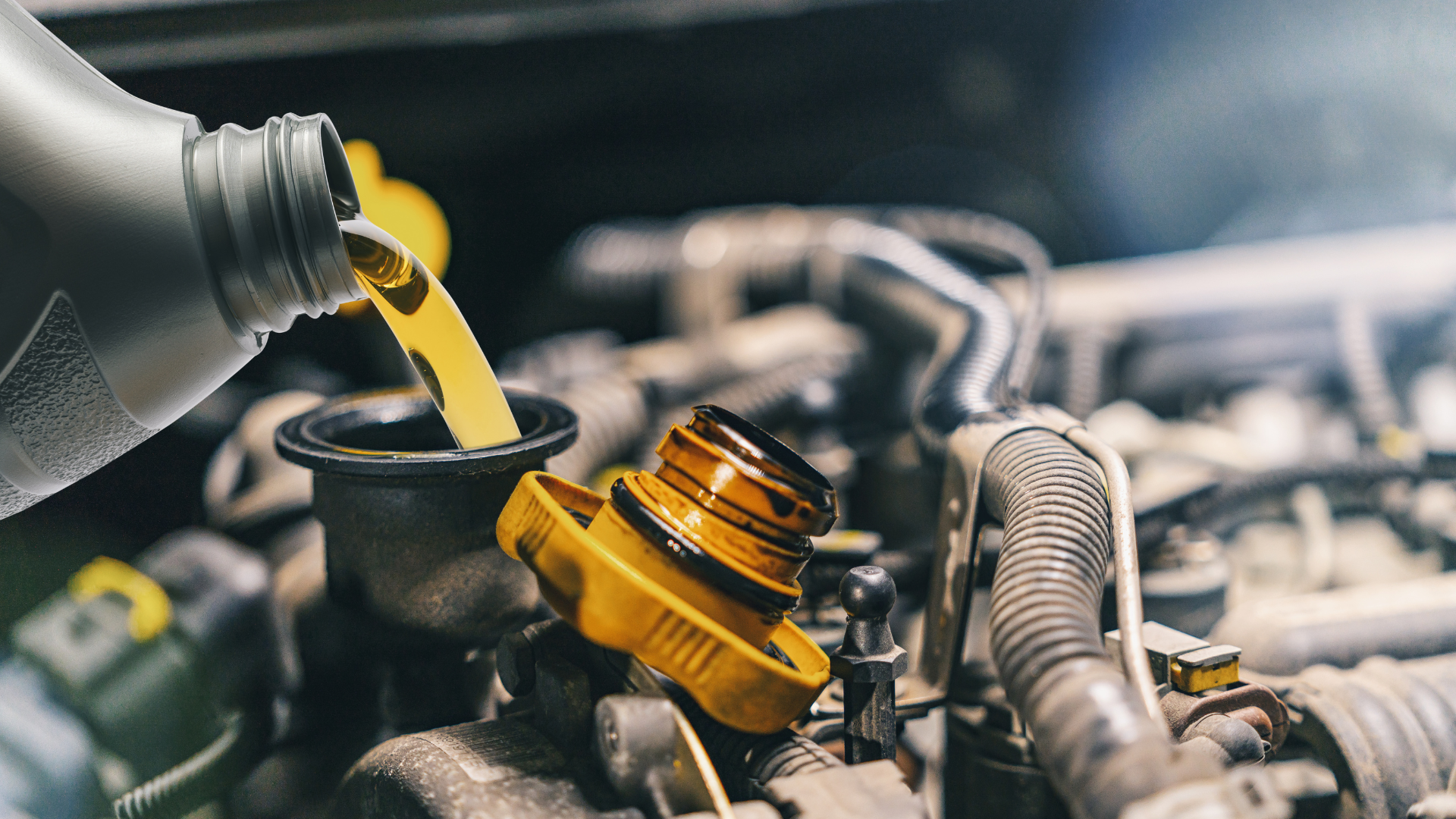 A person is pouring oil into a car engine.
