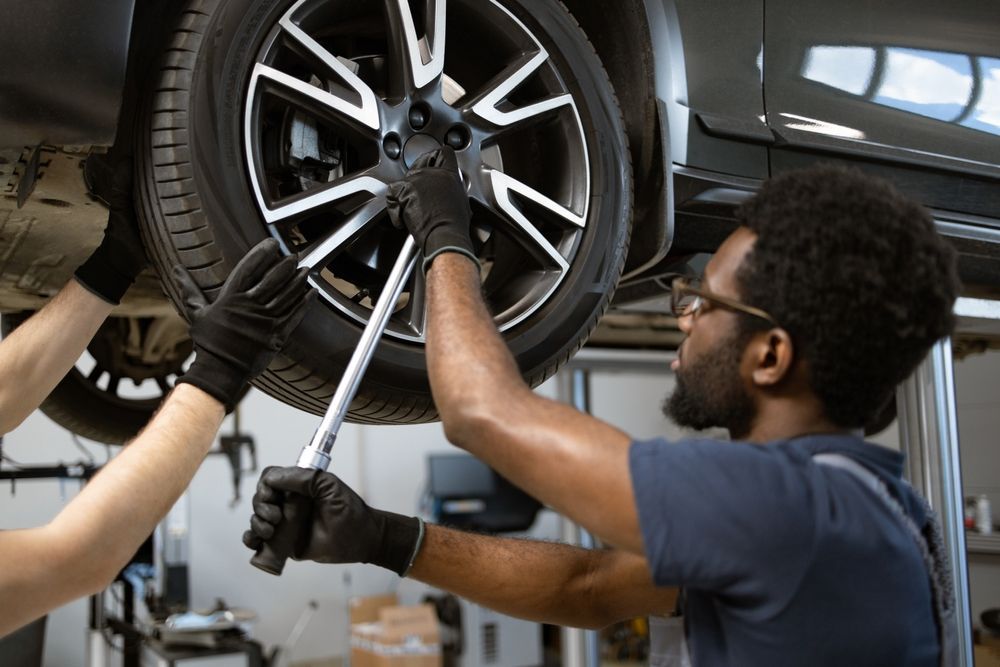 A man is changing a tire on a car in a garage.